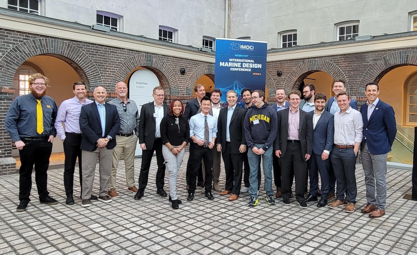 Larger group of smiling NAME students, faculty, and alumni at the International Marine Design Conferemce