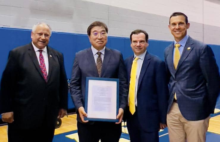 Four men stand together holding signed MoU for partnership